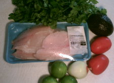 This is a picture of the ingredients that will be used for the recipe to make authentic Mexican seviche ( ceviche )  - including fish, limes, avocado, tomatoes, onion and cilantro.